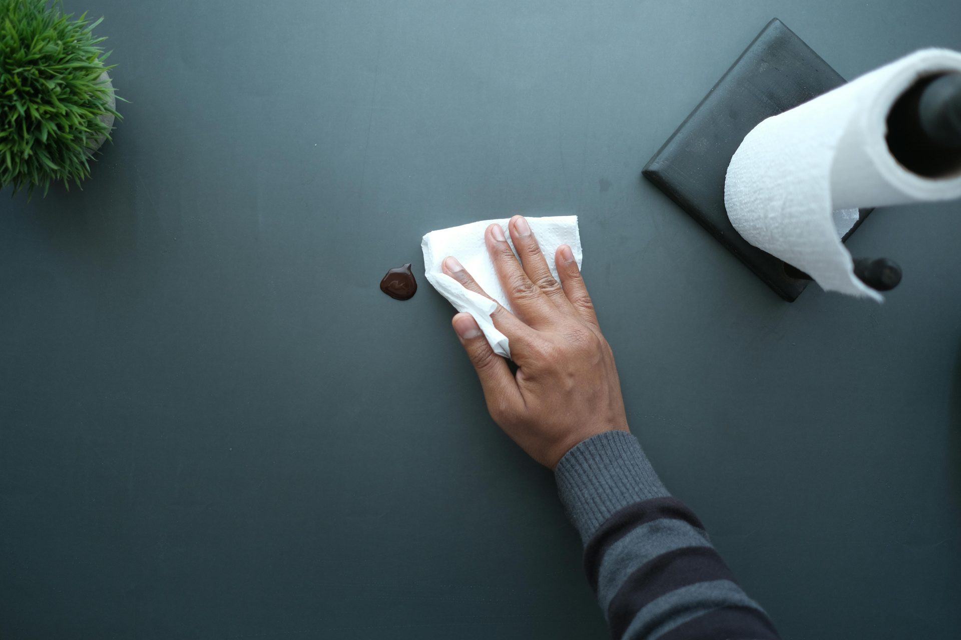 Hand wiping spilled liquid with paper towel.