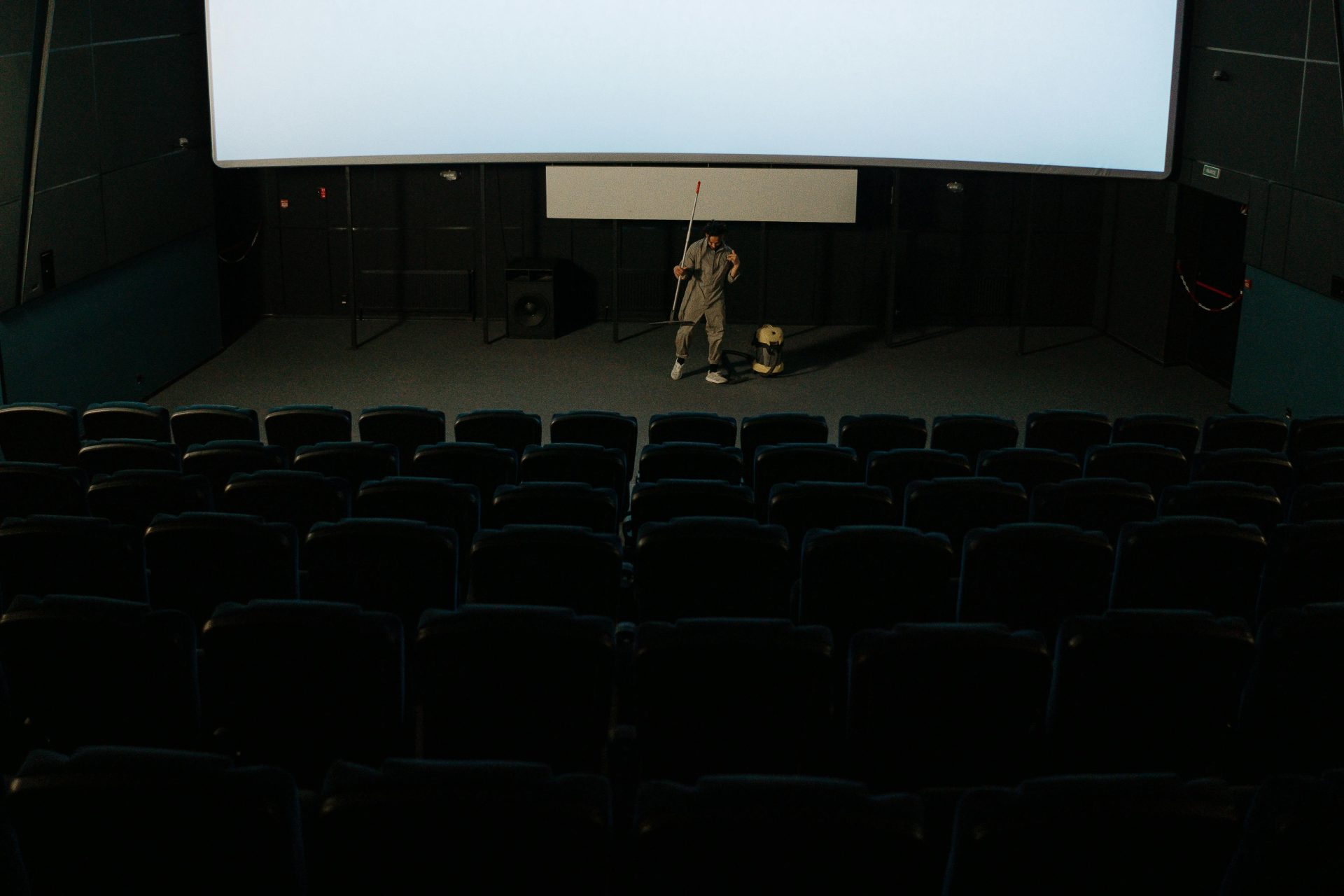 Janitor cleaning an empty movie theater.